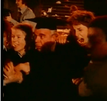 El profesor, ahora con birrete, es conducido por sus alumnos hacia las llamas.